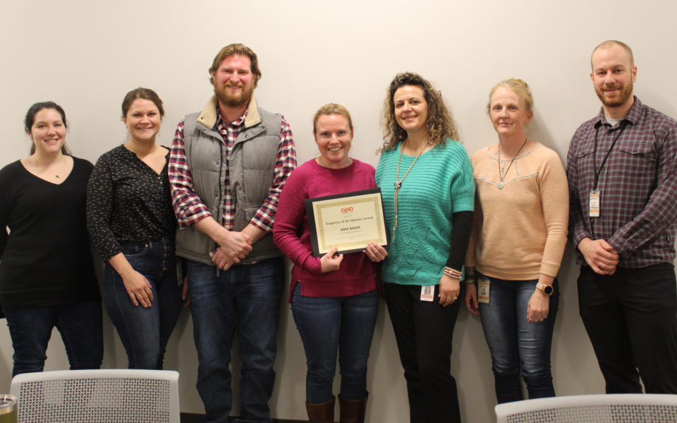 Group of employees with award winner and certificate of recognition